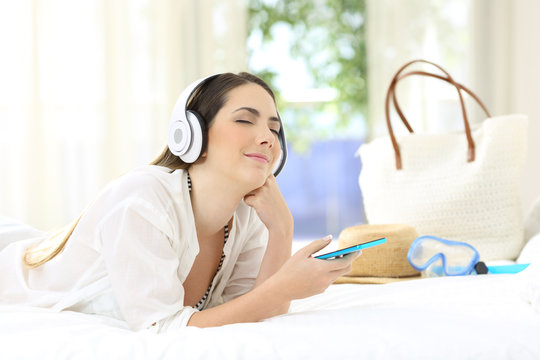 Woman listening to music relaxing in an hotel room