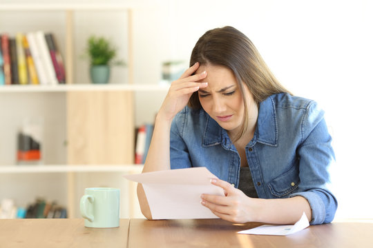 Worried woman reading bad news in a letter