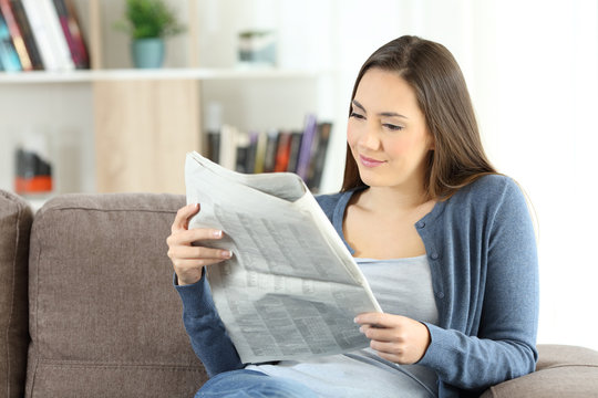 Woman reading a newspaper sitting on a couch