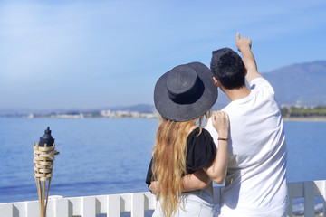 Young couple of travelers beackground sea / ocean. Happy loving couple on summer tropical beach. Vacation, tourism, hooneymoon. First minute / last minute. Happy, romantic couple dating.