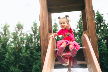 the girl descends from a wooden children's slide