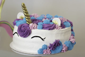 Close-up of unicorn cake with pink, blue, and purple colors and flowers. Made for birthday