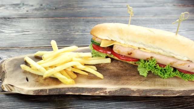 Sandwich and fries, wooden board. Tasty fast food close up.