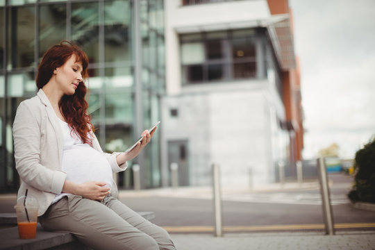 Pregnant businesswoman holding digital tablet