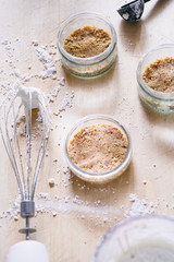 Preparation of a cheesecake on jar without baking it, biscuit mixed with butter are pressed in glass container