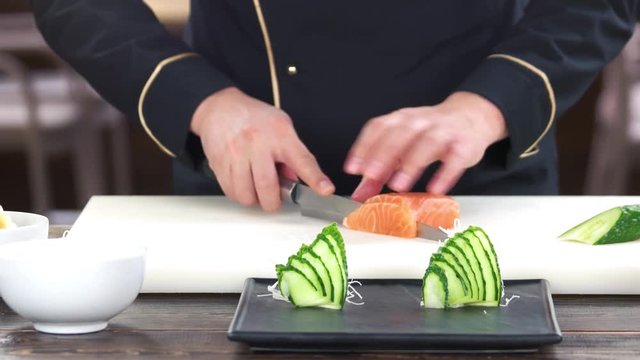 Hands cutting salmon. Chef preparing sushi ingredient.