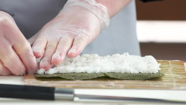 Hands preparing sushi close up. Rice and nori.