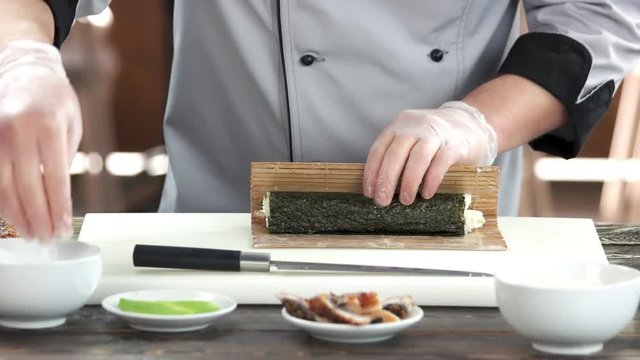 Chef shaping a sushi roll. Japanese food preparation, bamboo mat.