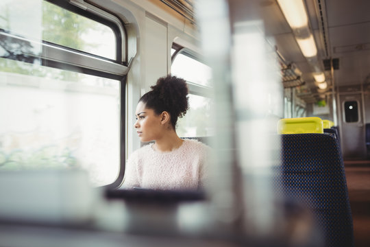 Thoughtful smart woman looking through window in train