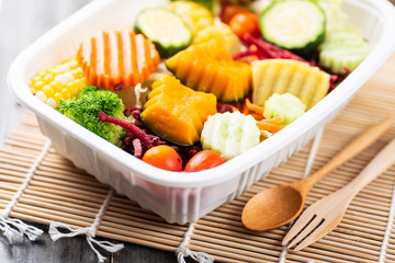 Vegetables salad in a plastic box with wooden spoon and fork, healthy food