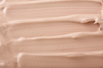 Fototapeta premium Beige liquid foundation makeup as a background. Top view. Flat lay pattern
