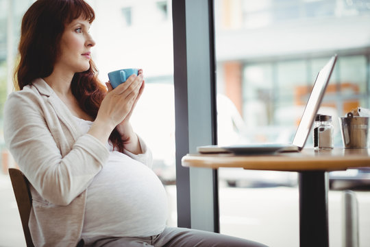 Pregnant businesswoman having coffee in cafeteria
