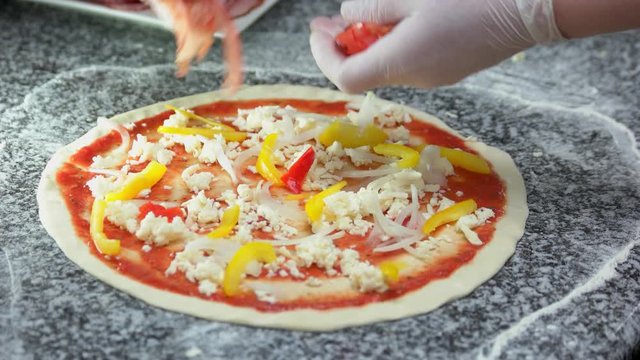 Chef making pizza close up. Mozzarella cheese, pepper and tomato.