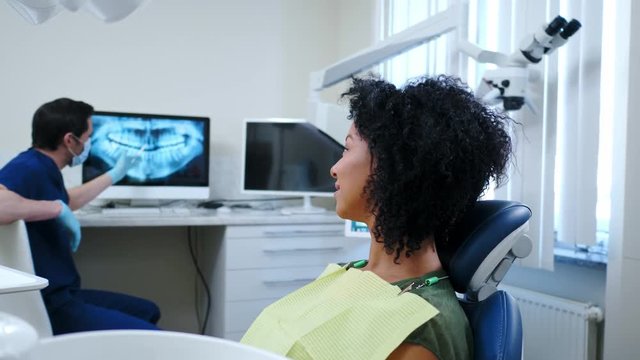 Man dentist showing x-ray results to his pacient.