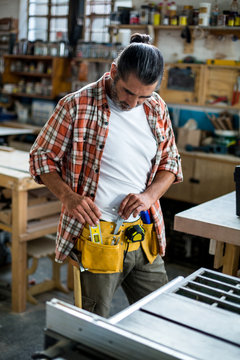 Carpenter removing spirit level from tool belt