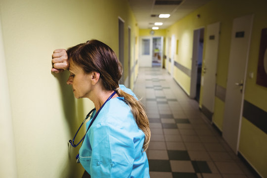 Depressed nurse standing in corridor