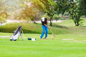 Obraz premium Man hitting golf ball on a golf course while on summer vacation.