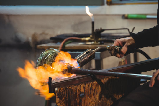 Glassblower giving final touch to a piece of glass with glassblowing torch
