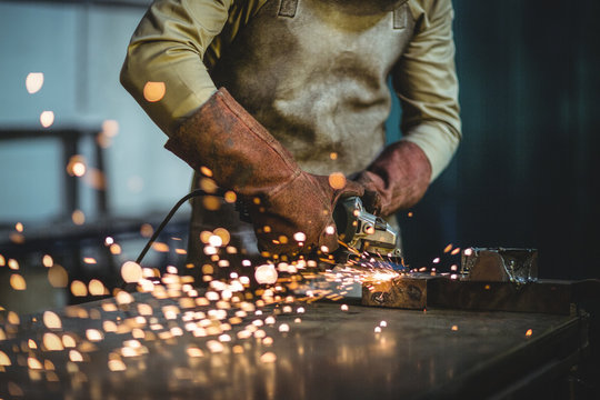 Mid-section of male welder working on a piece of metal