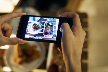 Taking smartphone photo of a dinner plate social media concept