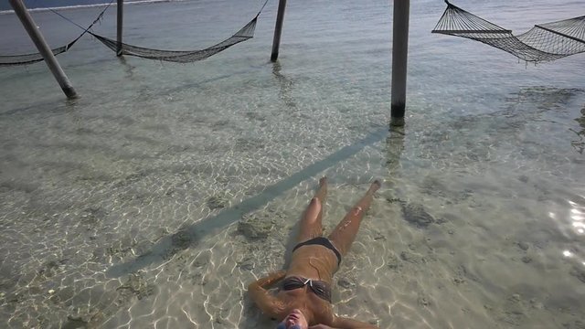Female tourist floating in shallow ocean waters in a warm summer day