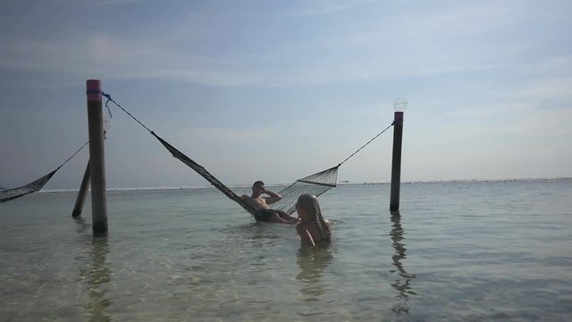 Young tourist couple relaxes in the ocean, man in a hammock in the sea
