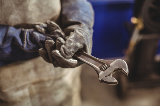 Mid-section of female welder holding wrench tool