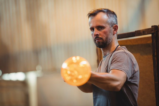 Glassblower shaping a glass on the blowpipe