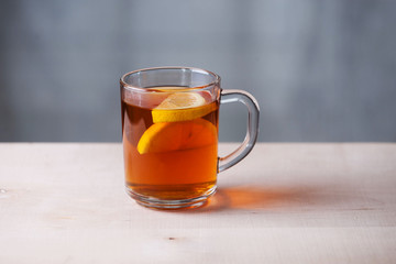 Transparent mug with lemon and tea and tea bag. Wood surface