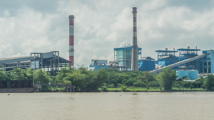 coal power plant on riverbank with barge full of coal in the dock.  Indonesia