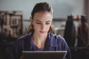 Female welder holding digital tablet