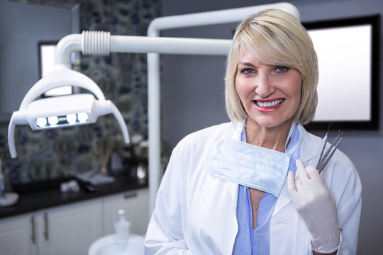 Portrait of smiling dentist holding dental tools