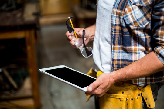 Carpenter using digital tablet in workshop