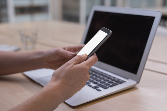 Close-up of woman using mobile phone at desk