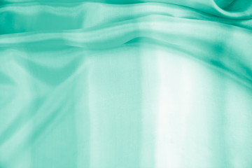 The texture of the satin fabric of green color for the background  
