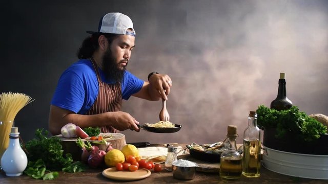 Handsome bearded cheef cook prepairing spaghetti on a kitchen, Chef cooks meal