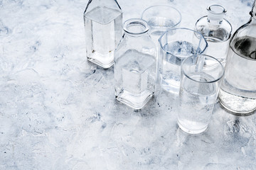 Drinks on the table. Pure water in jar and glasses on grey background space for text