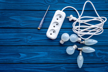 Electrical installation, wiring works. Bulbs and socket outlet on blue wooden background top view copy space