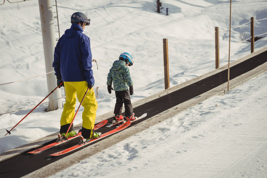 Father and daughter skiing on conveyor belt