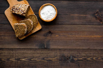 Homemade fresh bread sliced on cutting board on dark wooden background top view copy space