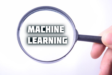 Businessman looking at a magnifying glass word:MACHINE LEARNING