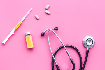 Fototapeta premium Medical examination and treatment concept. Stethoscope, syringe, pills on pink background top view copy space