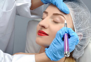 Microblading. Cosmetologist making permanent makeup. Attractive woman getting facial care and...