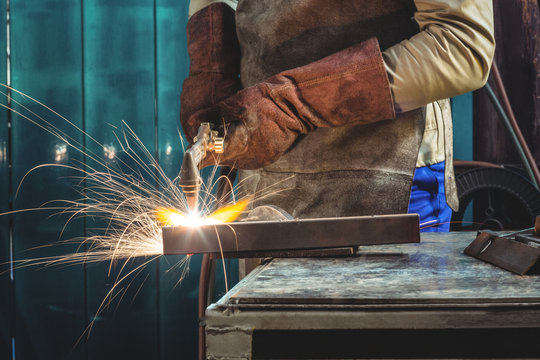 Mid-section of male welder working on a piece of metal