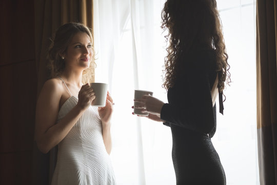 Bride and bridesmaid interacting while having a coffee