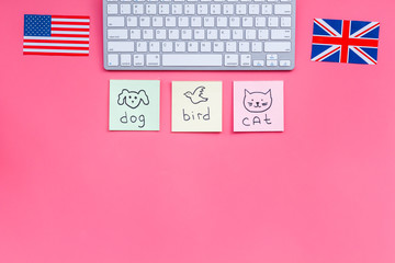 Study english online.English for kids. Elementary. British and american flags, computer keyboard, stickers with vocabulary on pink background top view copy space