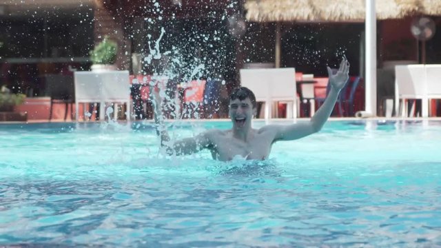 Young Man enthusiastically splashes pool water-