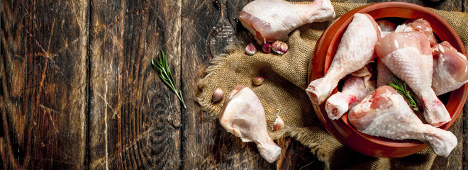 Raw chicken legs with garlic and spices in a bowl.
