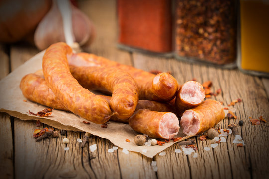 Sausages with spices on an old paper. On old wooden table.