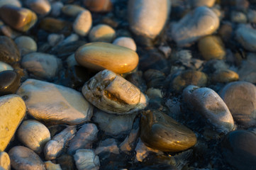 pebble stones on the sea beach, the rolling waves of the sea with foam